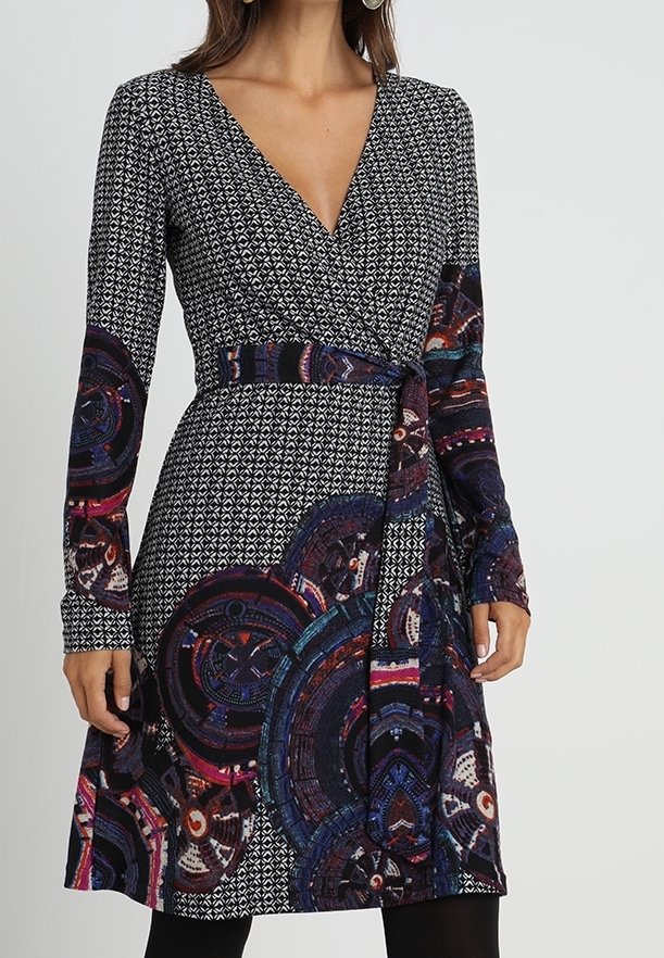Langärmeliges Wickelkleid aus dunklem Stoff mit geometrischen Mustern in Schwarz und Weiß, versehen mit bunten kreisförmigen Akzenten am Rock.