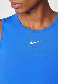 Modrá športová tielko vyrobené z hladkej, elastickej látky, s okrúhlym výstrihom a bielym logom Nike na hrudi.