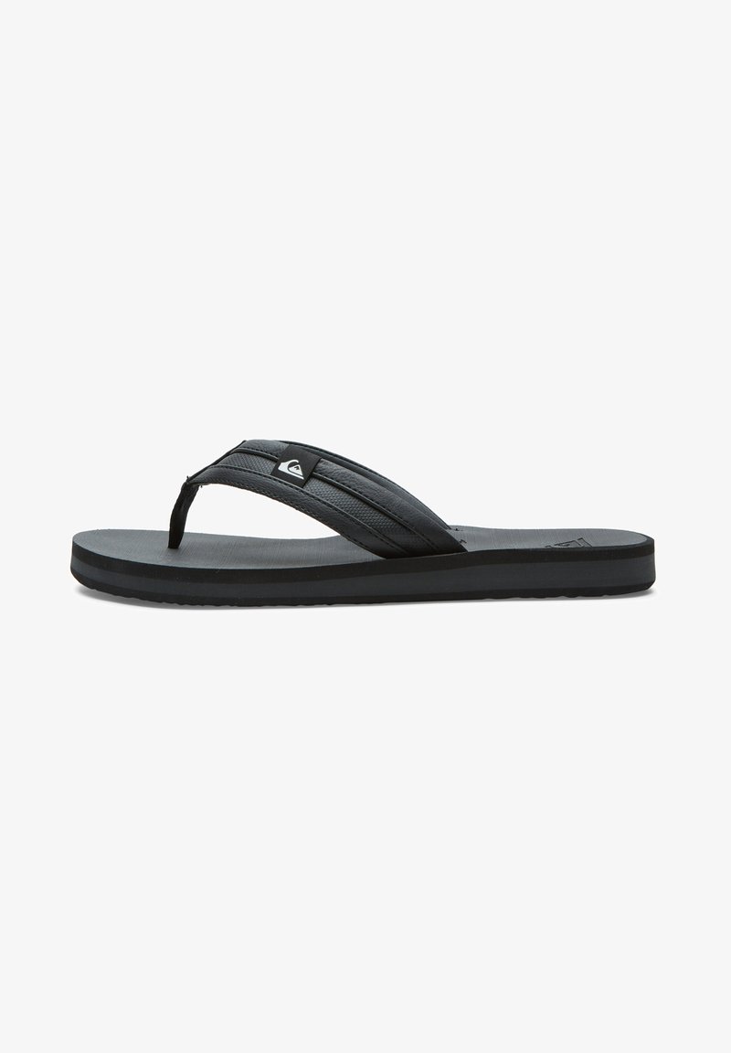 Sort flip-flop med en tekstureret rem, flad sål og diskret logo. Fremstillet af gummi og designet til afslappet brug.