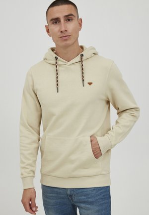 Beige hooded sweatshirt in soft fabric with patterned drawstrings and a front pocket. Features a small logo on the chest.