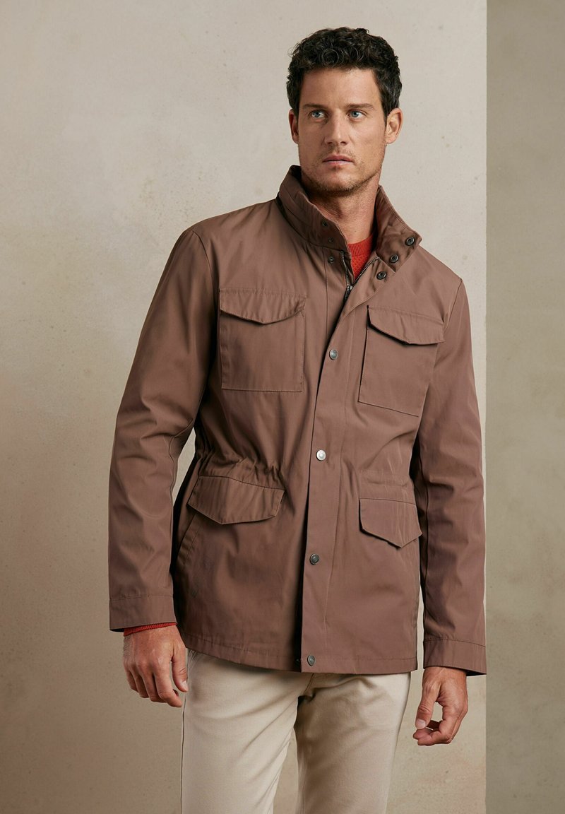 Brązowa, wodoodporna kurtka z podniesionym kołnierzem, czterema przednimi kieszeniami, ściągaczem w pasie i zatrzaskami. Gładka tekstura, casualowy styl.