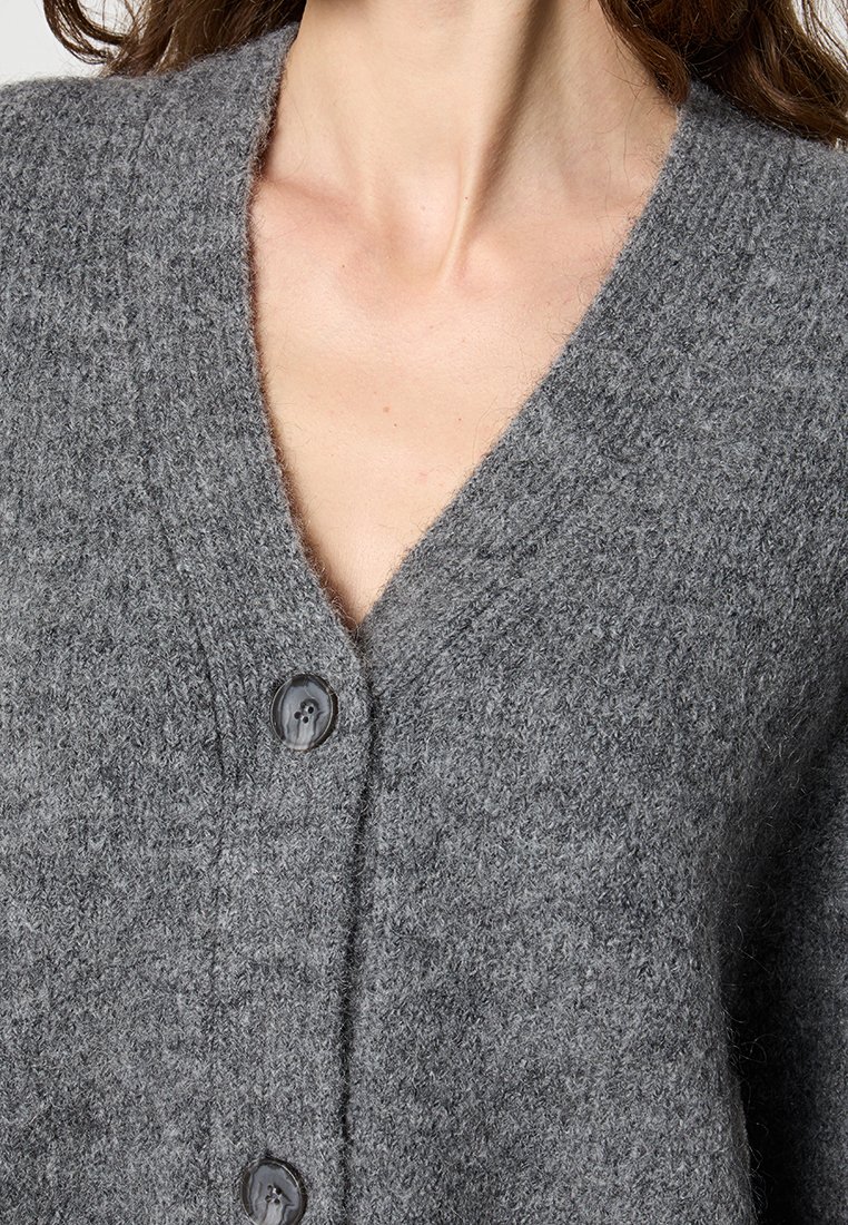 Grau Wollcardigan mit V-Ausschnitt, der eine strukturierte Optik aufweist, zwei große Knöpfe hat und ein weiches, flauschiges Erscheinungsbild bietet.