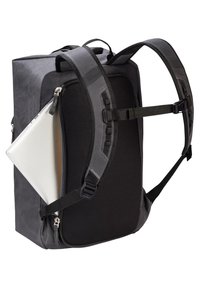 Schwarzer Rucksack mit verstellbaren Trägern, texturiertem Äußeren und einer Seitentasche, die einen silbernen Laptop hält. Mit Reißverschluss und robusten Beschlägen.