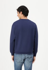 Felpa blu navy con maniche lunghe, collo rotondo e polsini a costine. Realizzata in un tessuto morbido, presenta un design semplice senza grafiche.