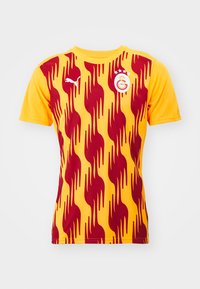 Maglietta da calcio a maniche corte di colore giallo con motivo a fiamma rossa; presenta il logo Puma e l'emblema della squadra sul lato sinistro del petto.