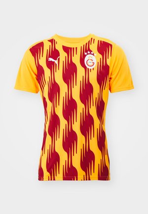 Kurzes Fußballshirt in Gelb mit rotem, flammenartigen Muster; verfügt über das Puma-Logo und das Teamwappen auf der linken Brust.