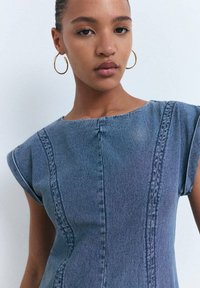 Rochie din denim albastru cu mâneci scurte, detalii de cusătură și guler rotund. Textură netedă și siluetă ajustată.