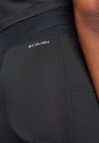 Svarta träningsbyxor med en texturerad hög midja, prydda med Columbia-logotypen och flatlock-sömmar.