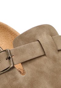 Sandalia de ante marrón con una correa ancha, hebilla de metal ajustable y plantilla texturizada. Cuenta con una plantilla de corcho y un acabado suave y liso.