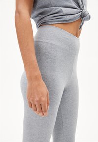 Gray cotton leggings with a smooth texture, high waistband, and stitching details, paired with a knotted gray top.