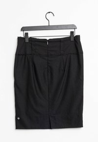 Musta kynähame mustalla henkareilla. Takana vetoketju, vyötäröllä laskokset ja helmassa halkio, jossa metallinen koriste.