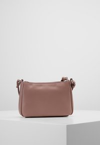 Kožená ramenní taška v decentní růžové barvě s obdélníkovým tvarem. Obsahuje zipové uzavření a texturovaný povrch. Nastavitelný popruh pro všestranné použití.