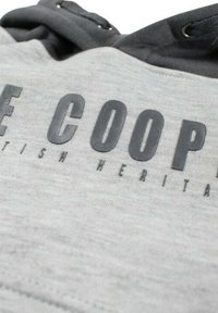 Tissu sweat-shirt gris avec lettrage noir en relief, affichant "COOPER" et "BRITISH HERITAGE". Hoodie avec cordons de serrage au niveau du col.