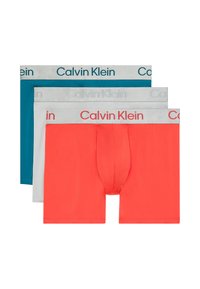 Tres pares de calzoncillos tipo boxers: azul verdoso, blanco y coral. Cuentan con cinturillas elásticas con el logo "Calvin Klein". Tela suave, de longitud media, ajuste clásico.