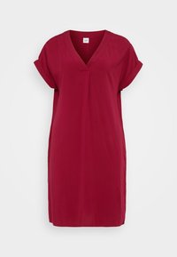 Robe rouge longueur genou avec un décolleté en V, manches courtes retroussées et tissu doux. Design simple sans motifs ni accessoires supplémentaires.