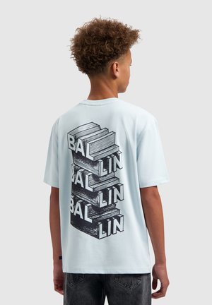 Tiener draagt lichtblauw T-shirt met zwart gestapeld boekenmotief en de tekst "BALLIN", verticaal herhaald op de achterkant.