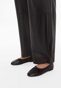 Czarne skórzane baleriny z marszczoną krawędzią i okr�ągłym noskiem, zestawione z szerokimi czarnymi skórzanymi spodniami z detalem guzika przy kostce.
