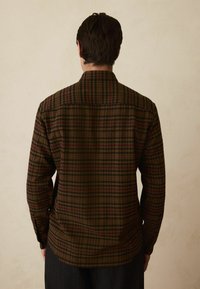 Camicia a quadri marrone e verde con maniche lunghe e colletto classico, con chiusura a bottoni sul retro e tessuto morbido.