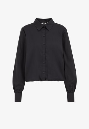 Mustas pikkade varrukatega särk, mis on valmistatud siledast kangast. Omab klassikalist kraed, nööpidega esist ja elastseid mansette. Lühendatud disain.