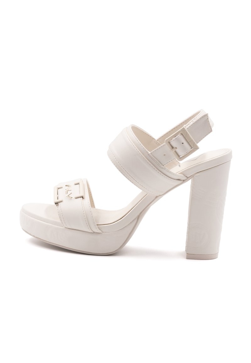 Valkoinen korkokenkä, jossa on alusta, paksut hihnat ja solki. Kannan pinta on teksturoitu ja se on neliömuotoinen.