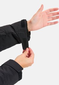 Zwarte jas mouw met een verstelbare klittenbandsluiting. Soepele stoftextuur, met een manchet dat is ontworpen voor een veilige pasvorm om de pols.