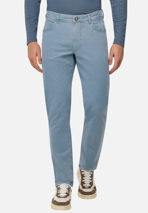 Jeans in cotone blu chiaro blend con cinque tasche, chiusura frontale a bottoni e gamba dritta, abbinati a sneakers bianche e marroni.