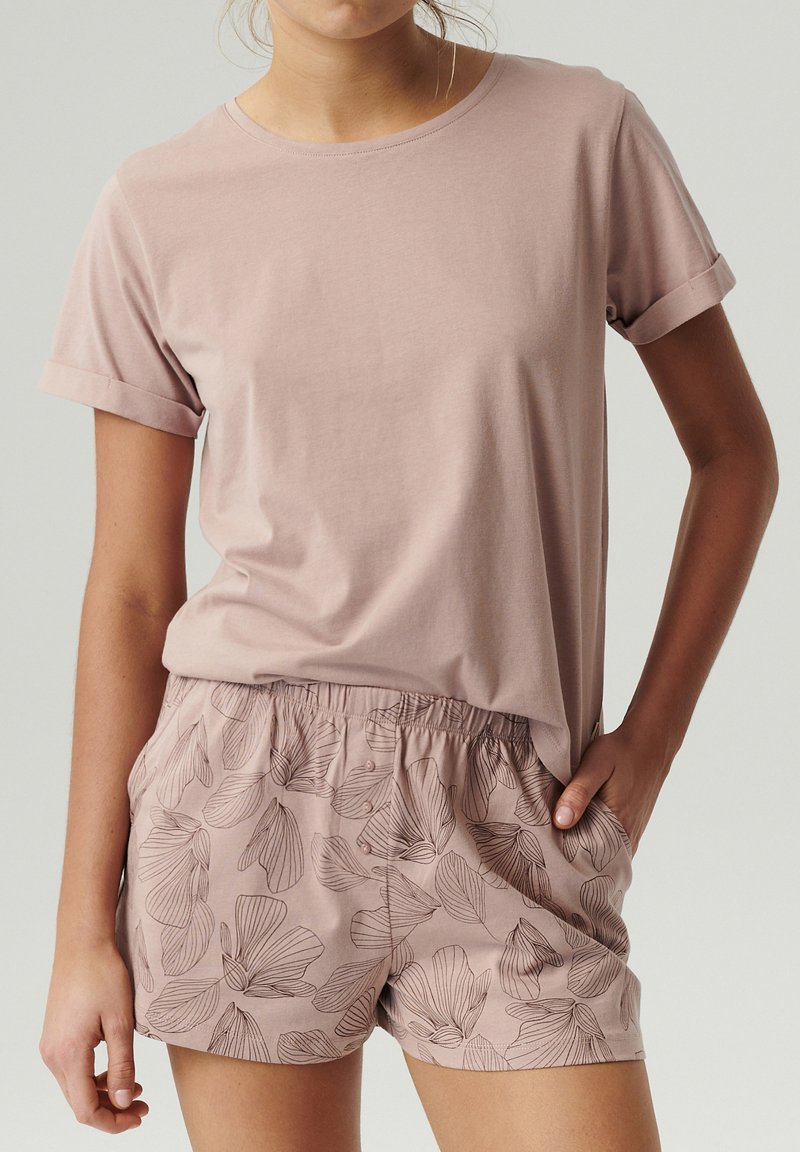 Różowa bawełniana koszulka z podwiniętymi rękawami, połączona z szortami w wzory z kwiatowymi motywami w ciemniejszych odcieniach różu.