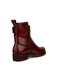 Braune Leder-Stiefelette mit einem seitlichen Reißverschluss, dekorativen Riemen und einer robusten Sohle mit Profil für Halt und Langlebigkeit.