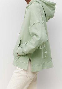 Sudadera verde menta con hombros caídos, bolsillo tipo canguro, dobladillo con abertura y acentos de texto en blanco. Fabricada con un tejido suave y texturizado.