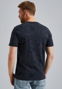 Camiseta de color azul marino con un patrón abstracto texturizado, de manga corta y cuello redondo. La tela parece suave, con un ligero brillo.