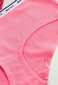 Pink cotton crop top with a smooth texture, featuring a rounded neckline and a black and white striped label along the upper edge.