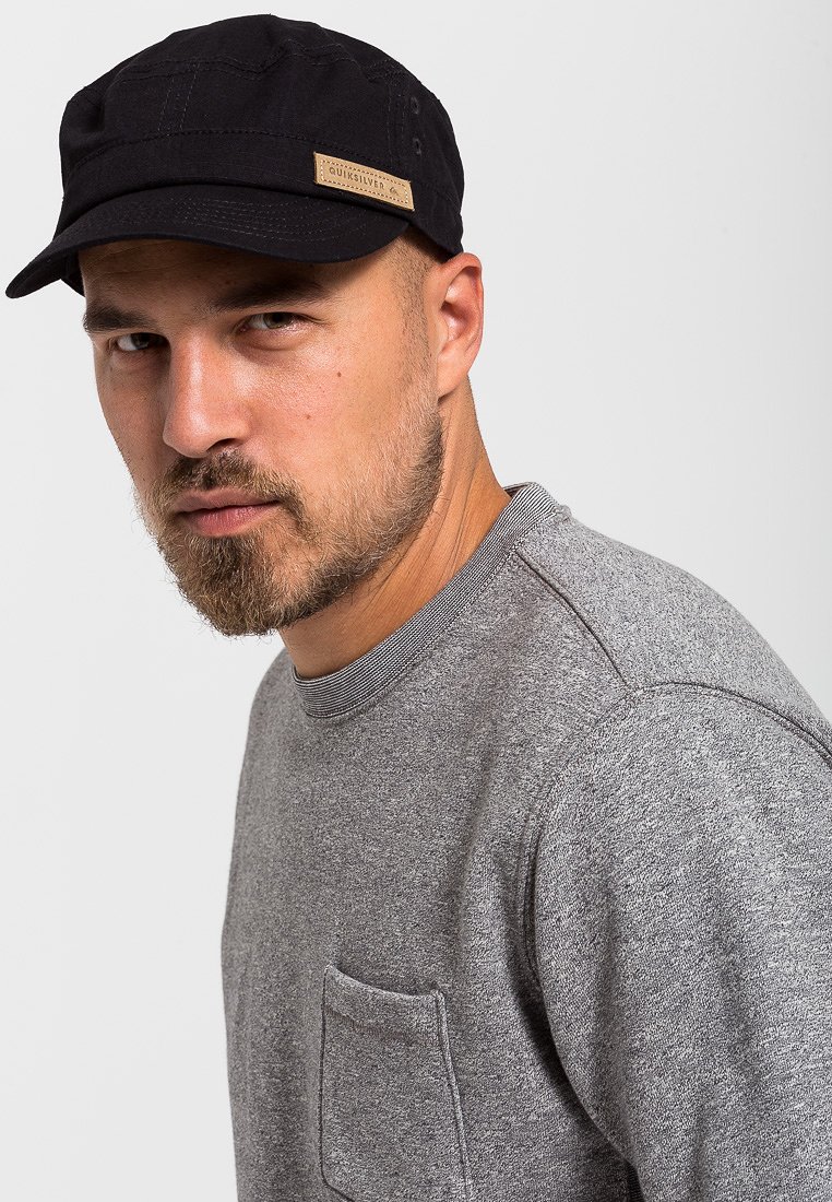 Čierna čiapka s mierne zakriveným okrajom a štruktúrovanou tkaninou. Svetlošedý sweatshirt s rebrovaným golierom a vreckom na hrudi.