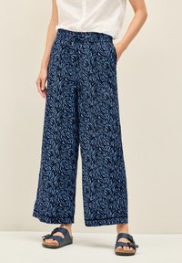 Marinblå vida byxor med ett bladmönster i ljusblått, med resårmidja och sidofickor. Mjuk tyg med en avslappnad passform.