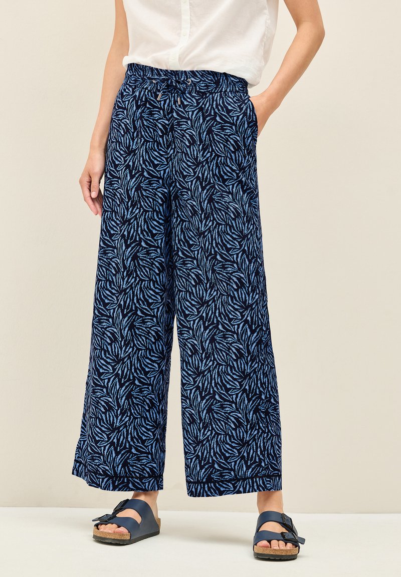 Marinblå vida byxor med ett bladmönster i ljusblått, med resårmidja och sidofickor. Mjuk tyg med en avslappnad passform.
