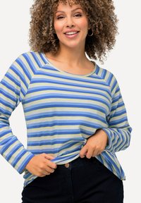 Blau- und grün gestreiftes Langarmshirt mit rundem Ausschnitt und lockerer Passform, aus weichem Stoff, kombiniert mit dunklen Hosen.