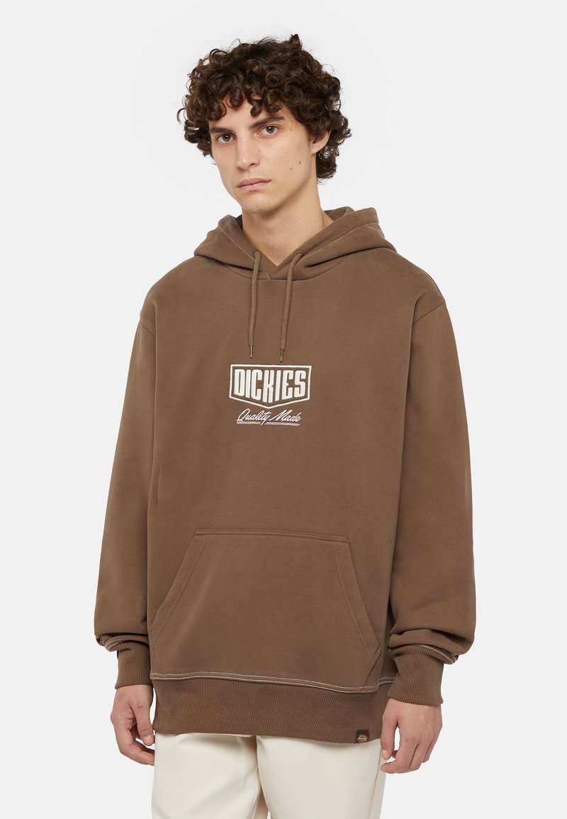 Brun huvtröja gjord av mjukt material med en framficka, som har en vit logo och sömmar vid nederkant och ärmar.