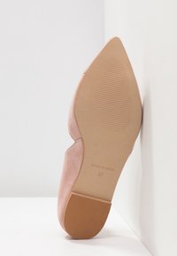 Chaussure en daim rose clair avec un bout pointu, une surface lisse, un design minimaliste et une semelle en caoutchouc texturée. Taille 37, fabriquée en Espagne.