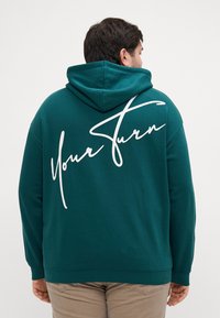 Felpa con cappuccio di colore verde acqua, dotata di tasca a canguro e con testo bianco in corsivo "Your Turn" sul retro. Tessuto morbido con polsini e orlo a costine.