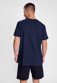 Mørkeblå bomulls t-skjorte med korte ermer, rund hals og en avslappet passform, kombinert med svarte shorts. Enkelt design, ingen synlige mønstre.