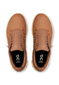 Des chaussures de sport imperméables marron avec un dessus texturé, un système de laçage intégré et des semelles rembourrées ; logo et nom du modèle visibles à l'intérieur.