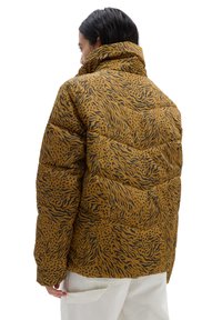 Wattierte Jacke in Senfgelb mit schwarzem Tiermuster, ausgestattet mit einem hohen Kragen und gestepptem Material. Die Rückansicht zeigt die Nähte und Passform.