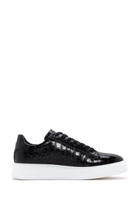 Zapatilla baja negra de cuero con patrón de cocodrilo, con cordones negros y una gruesa suela de goma blanca, vista desde el lado externo.