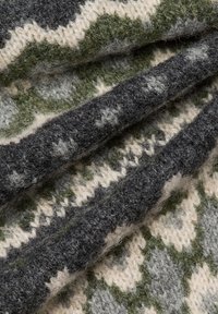 Gestrickter Stoff mit gefalteten Lagen in Grün, Grau und Cremefarben, der geometrische und Sterne-Muster aufweist.