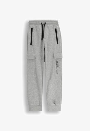 Szare bawełniane dresy z zamkami błyskawicznymi w kieszeniach, ściągaczami przy mankietach oraz bocznymi kieszeniami cargo. Na nodze znajduje się nadruk "JESTEŚMY MISTRZAMI".