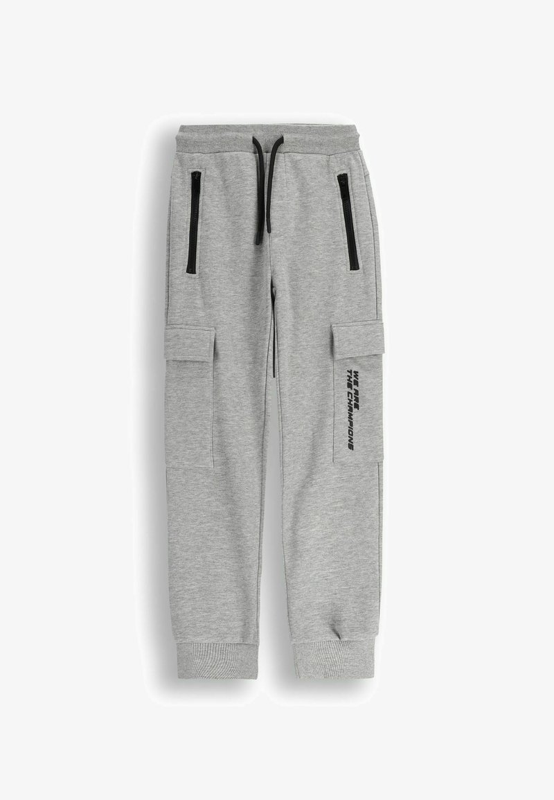 Szare bawełniane dresy z zamkami błyskawicznymi w kieszeniach, ściągaczami przy mankietach oraz bocznymi kieszeniami cargo. Na nodze znajduje się nadruk "JESTEŚMY MISTRZAMI".