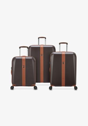 Tre valigie rigide di colore marrone scuro con accenti marrone chiaro, dotate di manici estraibili, cerniere e quattro ruote ciascuna.