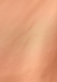 Perzikkleurige stof met een gladde textuur, met subtiele kleurovergangen en een lichte glans van de geweven vezels. Geen patronen of accenten aanwezig.