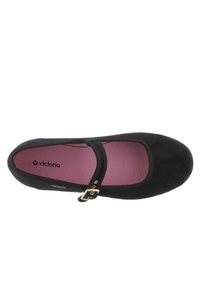 Zapato Mary Jane de ante negro con puntera redonda, suela plana, correa al tobillo con hebilla dorada y plantilla rosa con el logo "victoria".