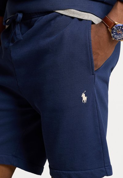 Pantaloni corti di cotone blu navy con vita elastica, tasche laterali e logo ricamato bianco sulla parte inferiore della gamba sinistra.