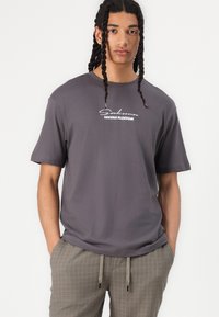 Camiseta gris de manga corta con un gráfico blanco de "Sakura Blossom" centrado en el pecho. Tejido suave, corte relajado y cuello redondo.